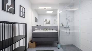 Ein modernes Badezimmer mit einer Duschkabine aus Glas, einem Waschtisch und einem schwarzen Metallgeländer.