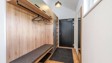 Un couloir avec un banc, une porte et un luminaire suspendu.