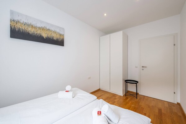 Ein Hotelzimmer mit zwei Betten, einem kleinen Tisch, einer Tür und einem Bild an der Wand.