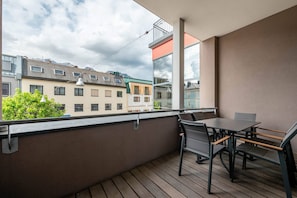 Ein Balkon mit Tisch und Stühlen, der auf eine Häuserreihe mit einem Berg im Hintergrund blickt.