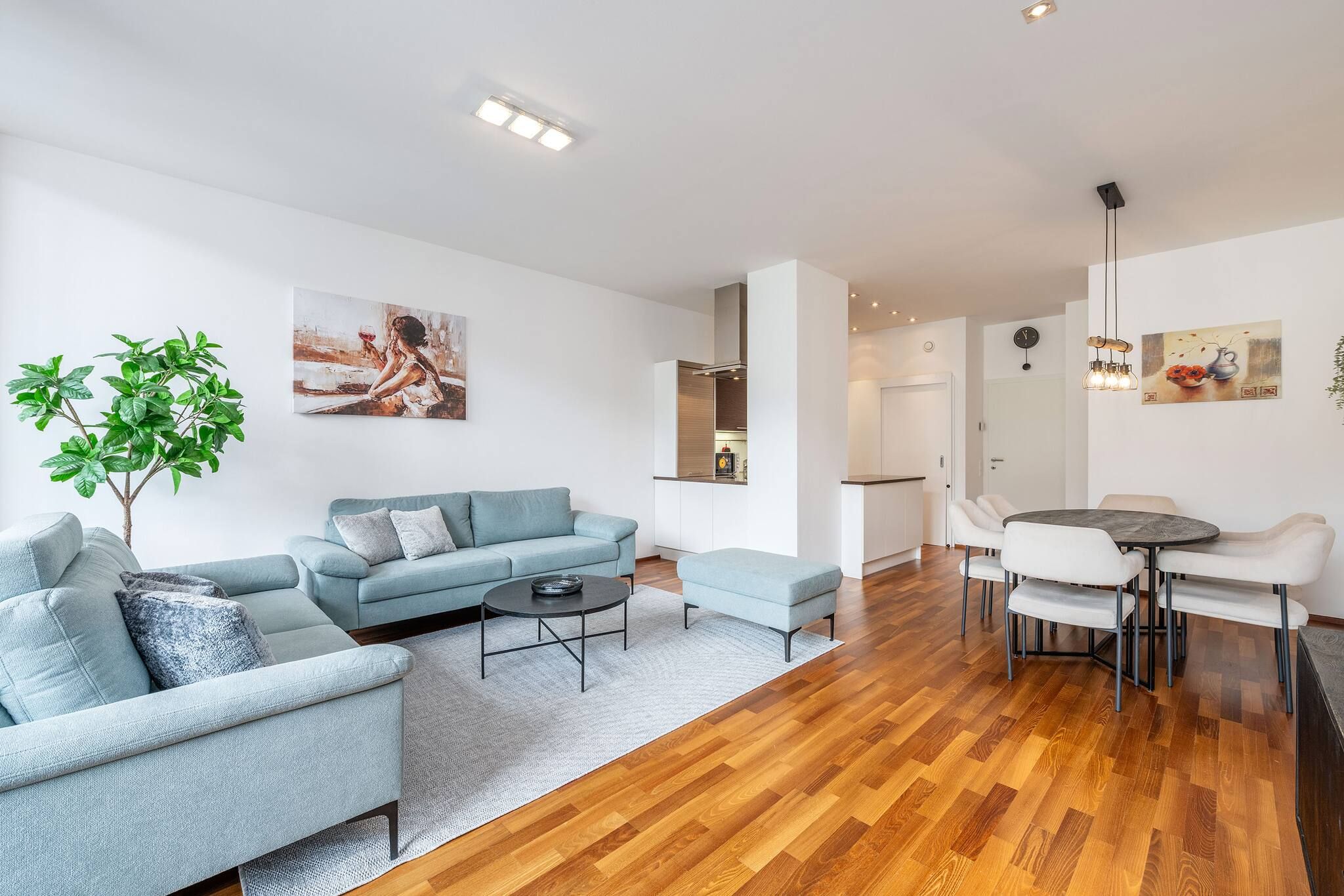 Ein modernes Wohnzimmer mit Sofa, Couchtisch und Essbereich mit Stühlen.