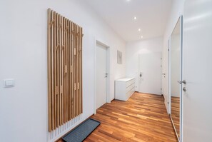 A hallway with wooden flooring, white walls, and a door leading to a bathroom. - CityFLAT 38 Schladming (Schladming)
