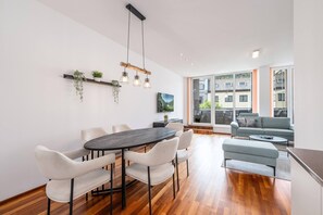 A modern living room with a dining area, large windows, and a view of the outside. - CityFLAT 38 Schladming (Schladming)