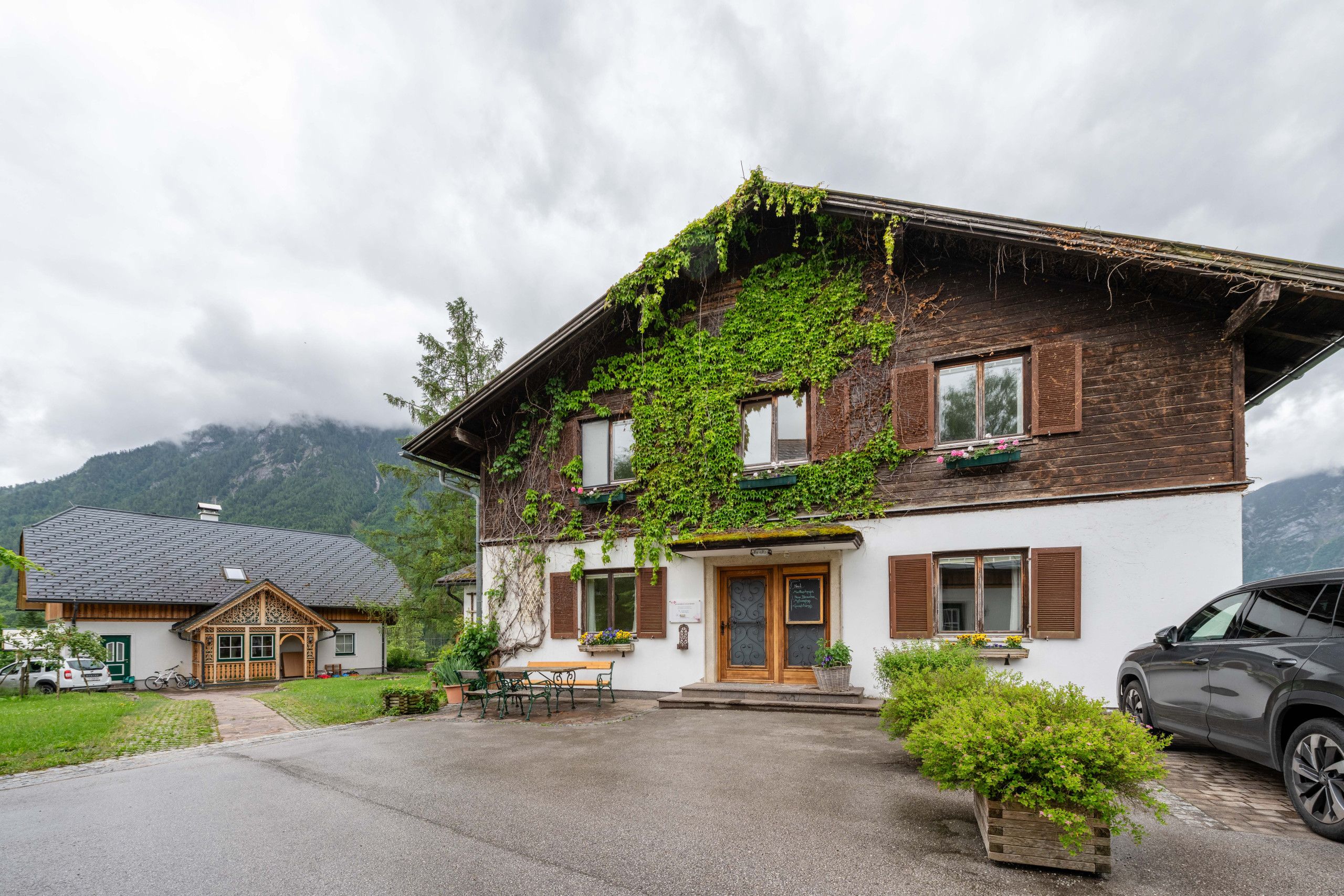 En tvåvånings chalet med en träfasad, en balkong med grönska och en asfalterad uppfart.