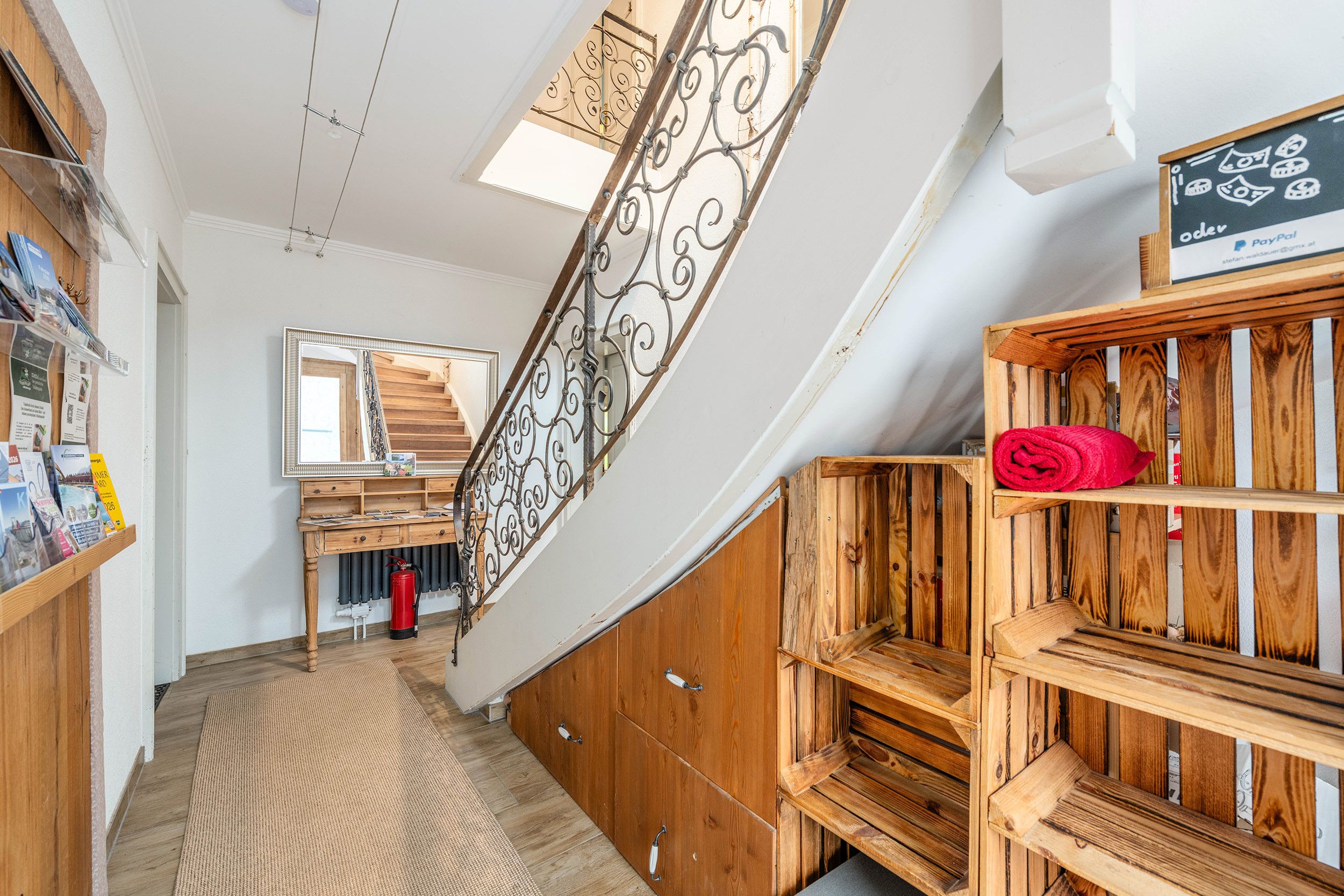 Eine Holztreppe mit Metallgeländer, ein Holztisch mit Spiegel und ein rotes Handtuch auf einer Holzablage.