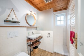 A bathroom with a wooden ceiling, a white sink, a mirror, a window, and a towel rack. - Stanglhof - Apartment Sarstein (Bad Aussee)