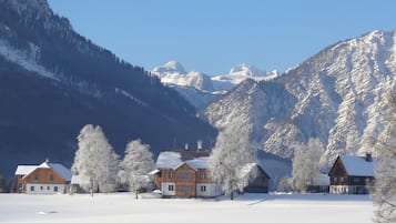 Ett snötäckt landskap med en rad trähus, en klar himmel och berg i bakgrunden.