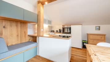 A compact kitchen with a built-in stove, a coffee machine, and a sink.