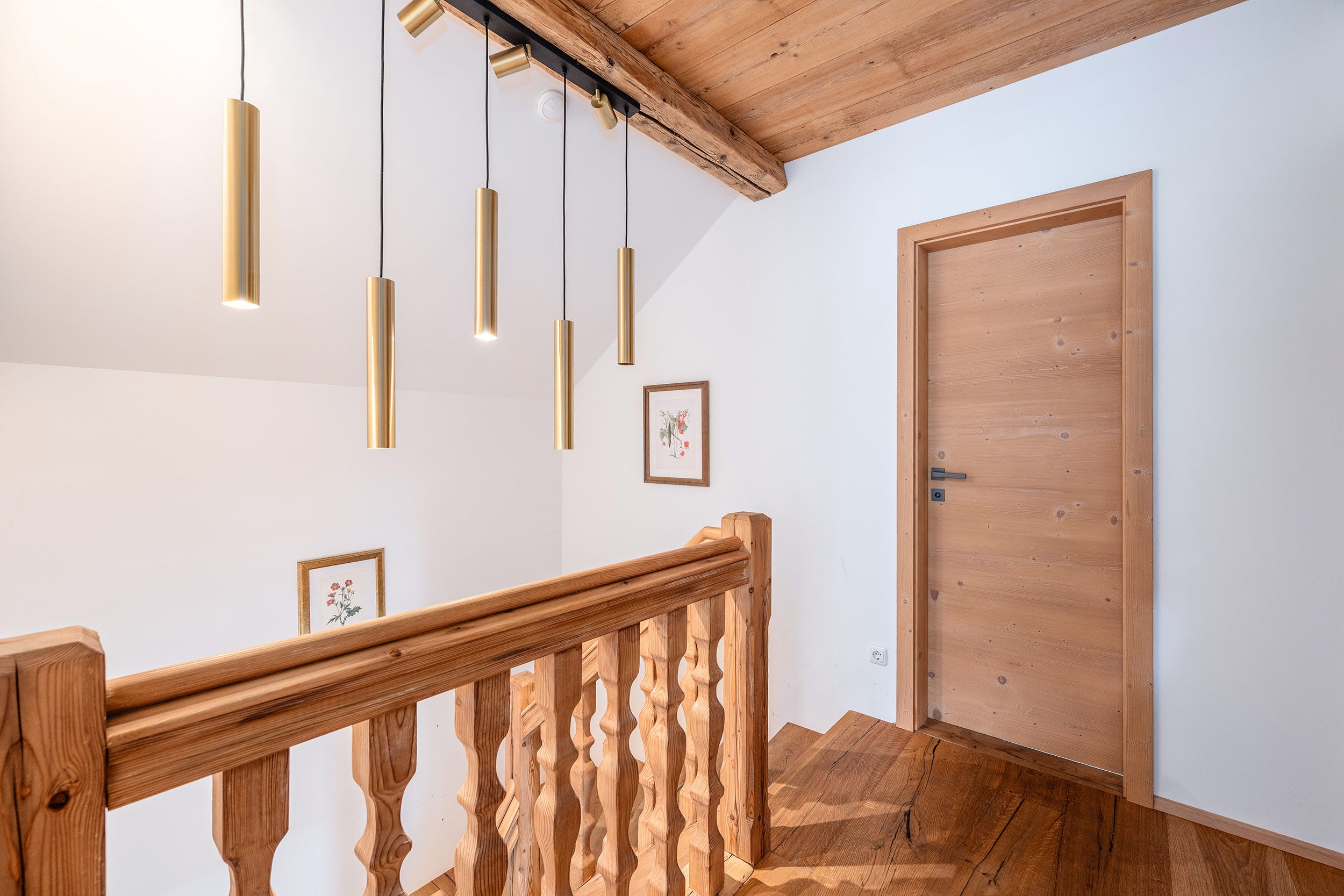 A wooden staircase with a railing, a wooden door, and pendant lights.