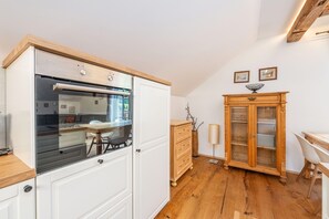 Una cucina compatta con forno a incasso, un pensile in legno e un'area pranzo con tavolo e sedie.