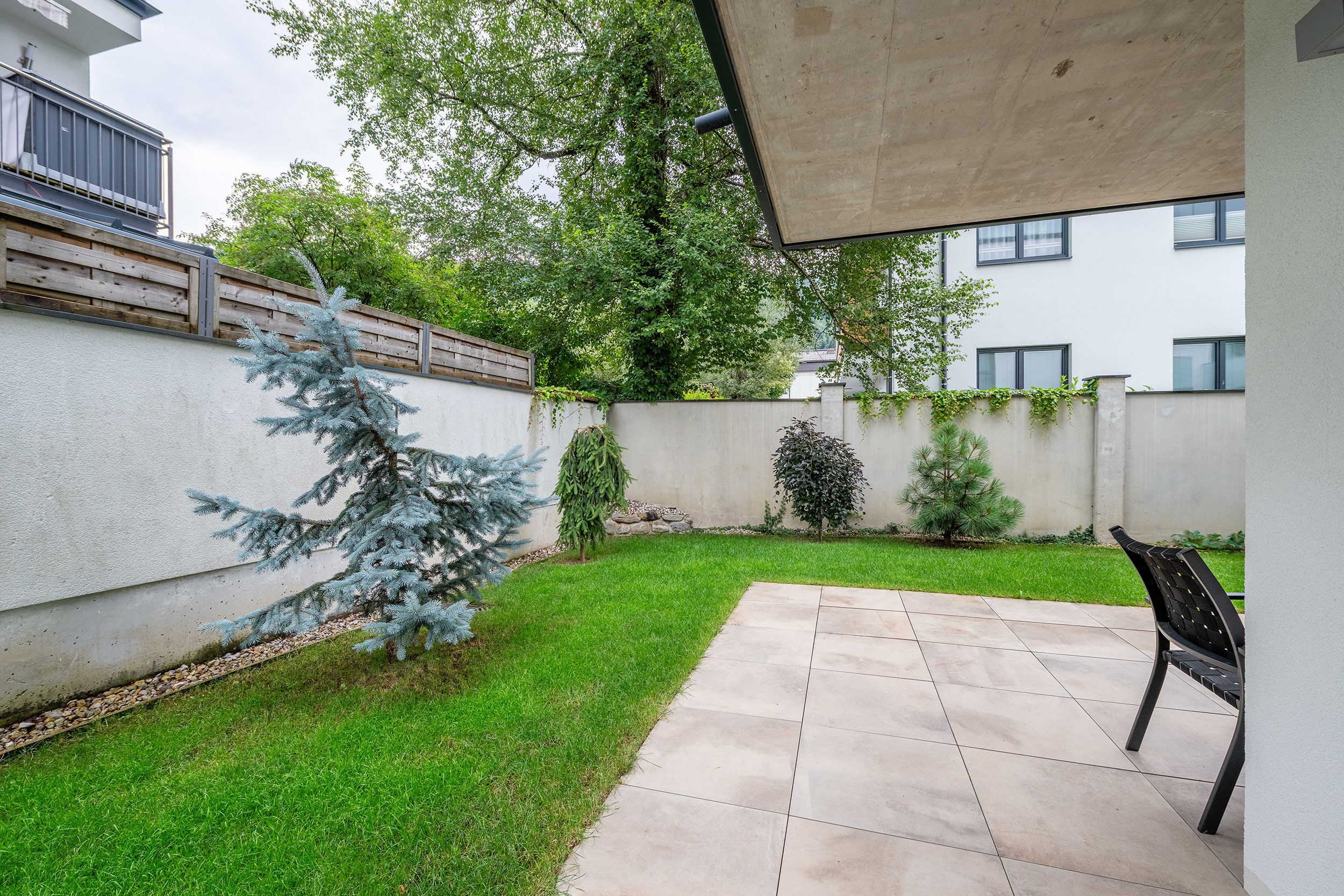 Un patio con piso de baldosas, un banco y un árbol pequeño.