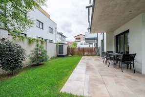 Une cour intérieure aménagée en espace résidentiel, avec un patio, une petite pelouse et un coin repas doté de mobilier d’extérieur.