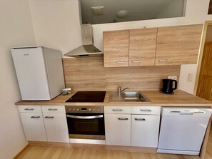 Eine moderne Küche mit Einbauofen, Geschirrspüler, Spüle und Holzschränken.