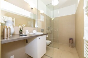 Ein modernes Badezimmer mit einer Duschkabine aus Glas, einem weißen Waschbecken und einem Waschtisch mit Toilettenartikeln.