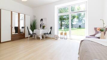 Ein modernes Schlafzimmer mit großem Fenster, einem Bett, einem Schreibtisch mit Stühlen und einem Kleiderschrank.