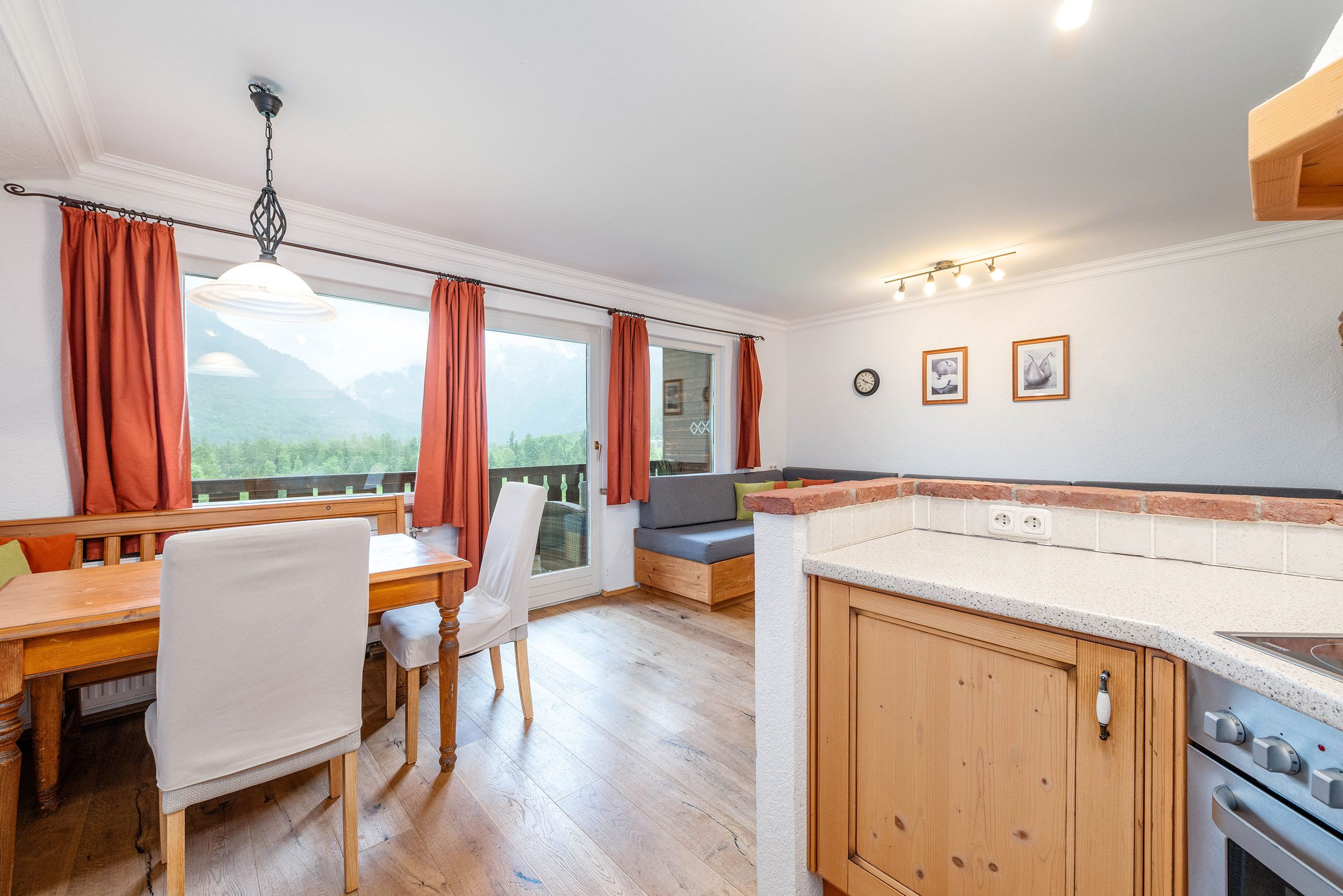 Une cuisine moderne avec des meubles en bois, un coin repas comprenant une table et des chaises, et une vue sur l’extérieur.