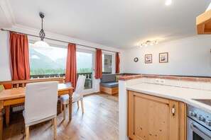 Une cuisine moderne avec des meubles en bois, un coin repas comprenant une table et des chaises, et une vue sur l’extérieur.