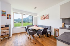 Une cuisine moderne avec un coin repas, un plancher en bois et une vue sur un paysage montagneux.