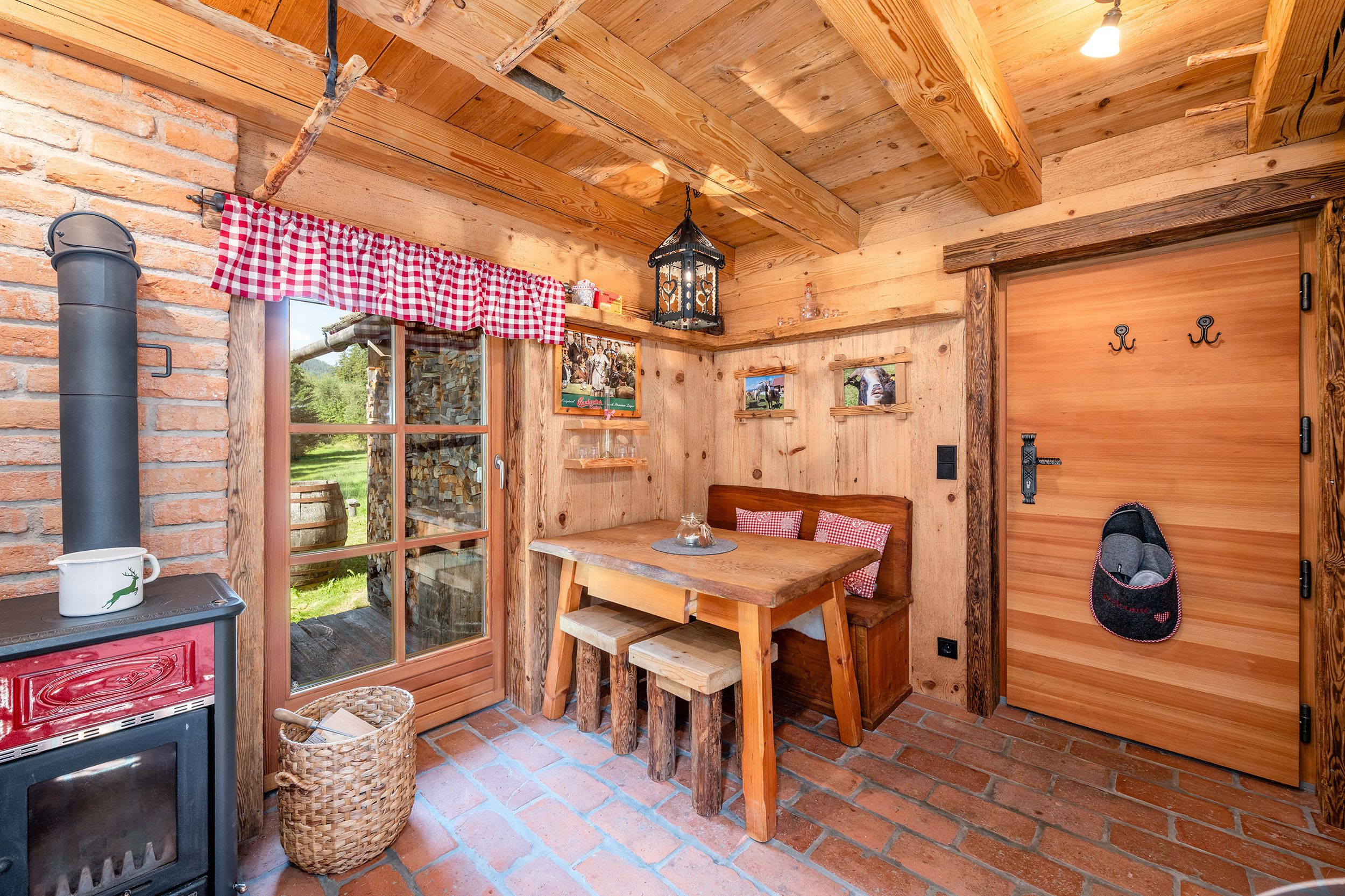 Ein rustikales Holzinterieur mit Kamin, Esstisch und Bank.