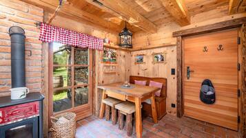 Ein rustikales Holzinterieur mit Kamin, Esstisch und Bank.