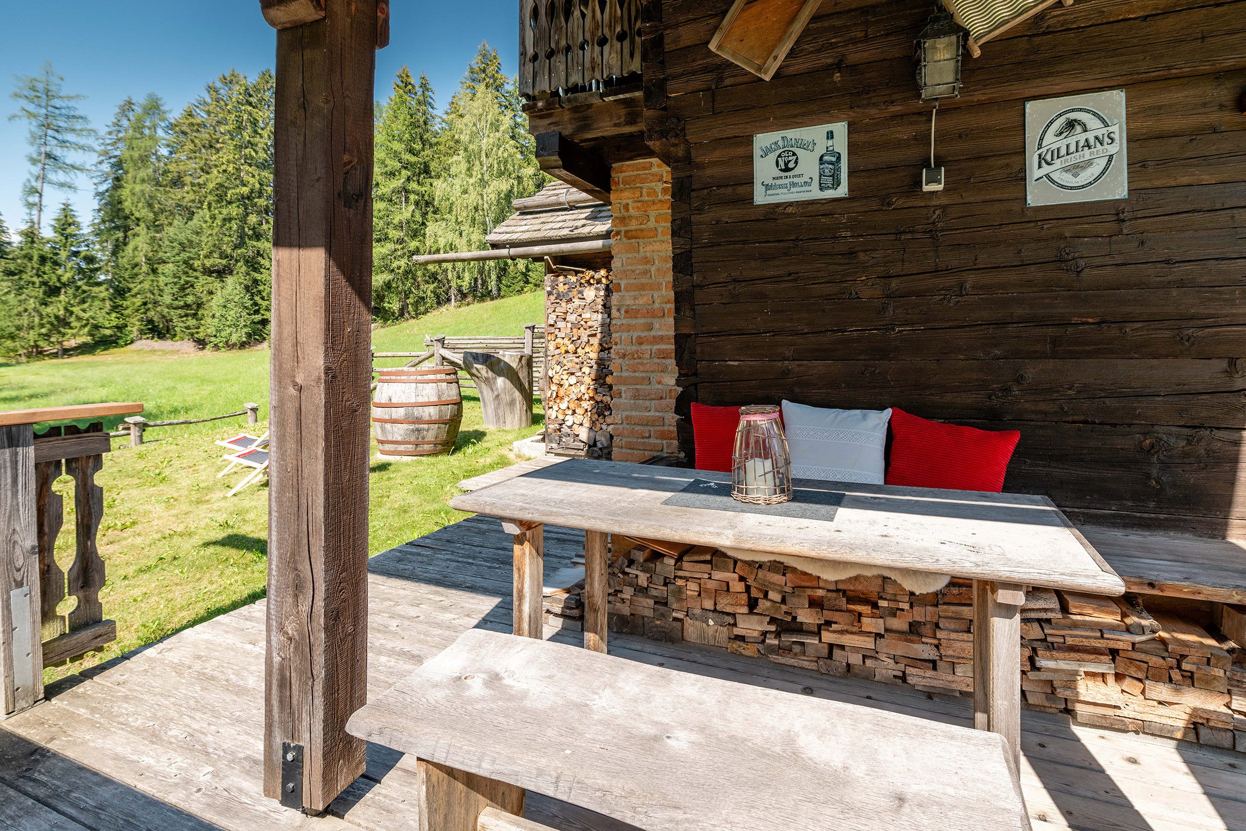 Eine rustikale Holzhütte mit Kamin aus Stein, einem Tisch mit Kerze und einer Bank mit Kissen.
