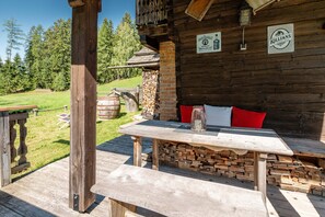 Eine rustikale Holzhütte mit Kamin aus Stein, einem Tisch mit Kerze und einer Bank mit Kissen.
