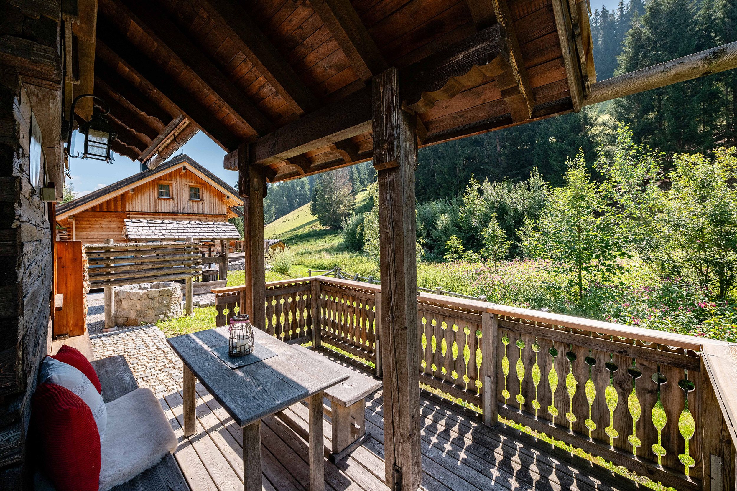Eine Holzhütte mit einem Balkon mit Blick auf ein bewaldetes Tal.