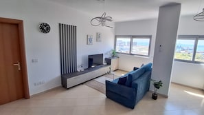 Un salon moderne avec un canapé, un téléviseur et des œuvres d’art accrochées au mur.