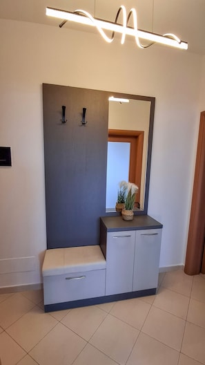 Une salle de bain moderne avec un banc, un miroir et un luminaire.