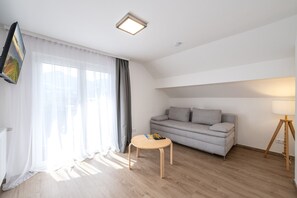 Una sala moderna con un sofá gris, una mesita redonda y una lámpara de pie.