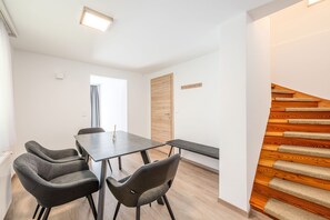 A modern interior with a dining table, four chairs, a bench, a wooden door, and a wooden staircase. - Alpenpanorama Assach 2 (Aich-Assach)