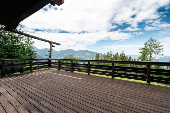 Um deck de madeira com vista para montanhas e árvores.