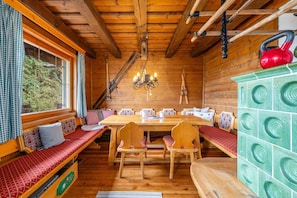 Interior de uma cabana de madeira, com uma mesa de jantar, bancos e um armário verde.