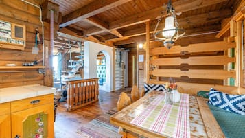 Ein gemütliches Blockhaus-Interieur mit einem Holzesstisch, einer Bank und einer Treppe, die zu einer oberen Ebene führt.