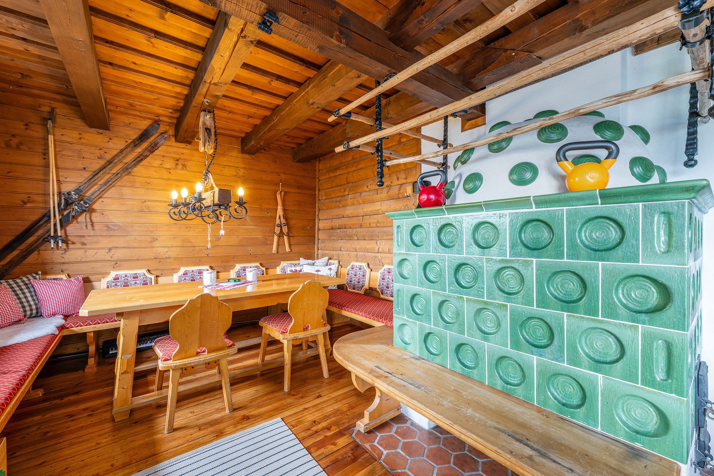 Ein Holzinnenraum mit Holztisch, Bänken und einem grünen Schrank mit kreisförmigen Mustern.