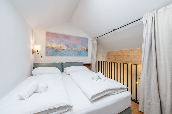 Ein Schlafzimmer mit einem Bett, Kissen, einer Wandlampe und einem Gemälde.