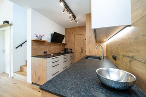 Eine moderne Küche mit Holzschränken, einer schwarzen Arbeitsplatte und einem Edelstahl-Spülbecken.