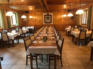 Una taula de dinar llarga amb caires, preparada per a una menjada en una habitació amb parets i sostre de fusta.