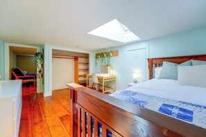 Ein Schlafzimmer mit Bett, Schreibtisch und Stuhl. Über dem Bett befindet sich ein Oberlicht.