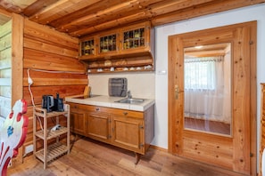 A wooden cabin interior with a kitchen area, including wooden cabinets, a sink, and a window with curtains. - Planai 66 - Bergstube (Schladming)