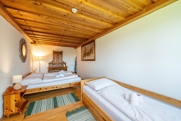 A room with two wooden beds, a wooden nightstand with a lamp, a mirror, a wooden dresser, and a framed picture on the wall. - Planai 66 - Bergstube (Schladming)