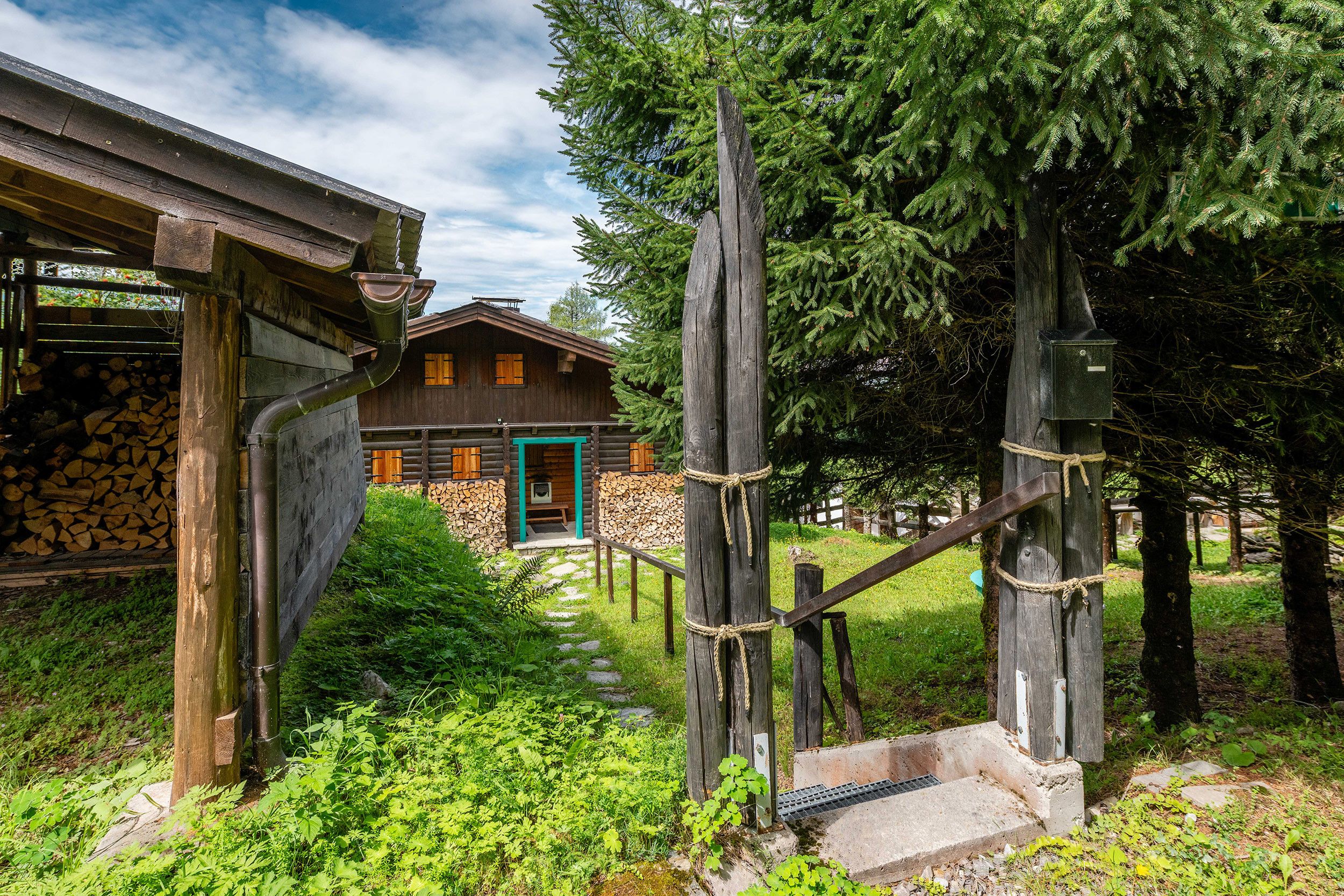 Une cabane rustique en bois, avec un mur en pierre, un escalier en bois et une clôture en bois.