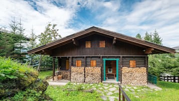 Eine Holzhütte mit einer Holztür, einer Veranda und einem Holzstapel.