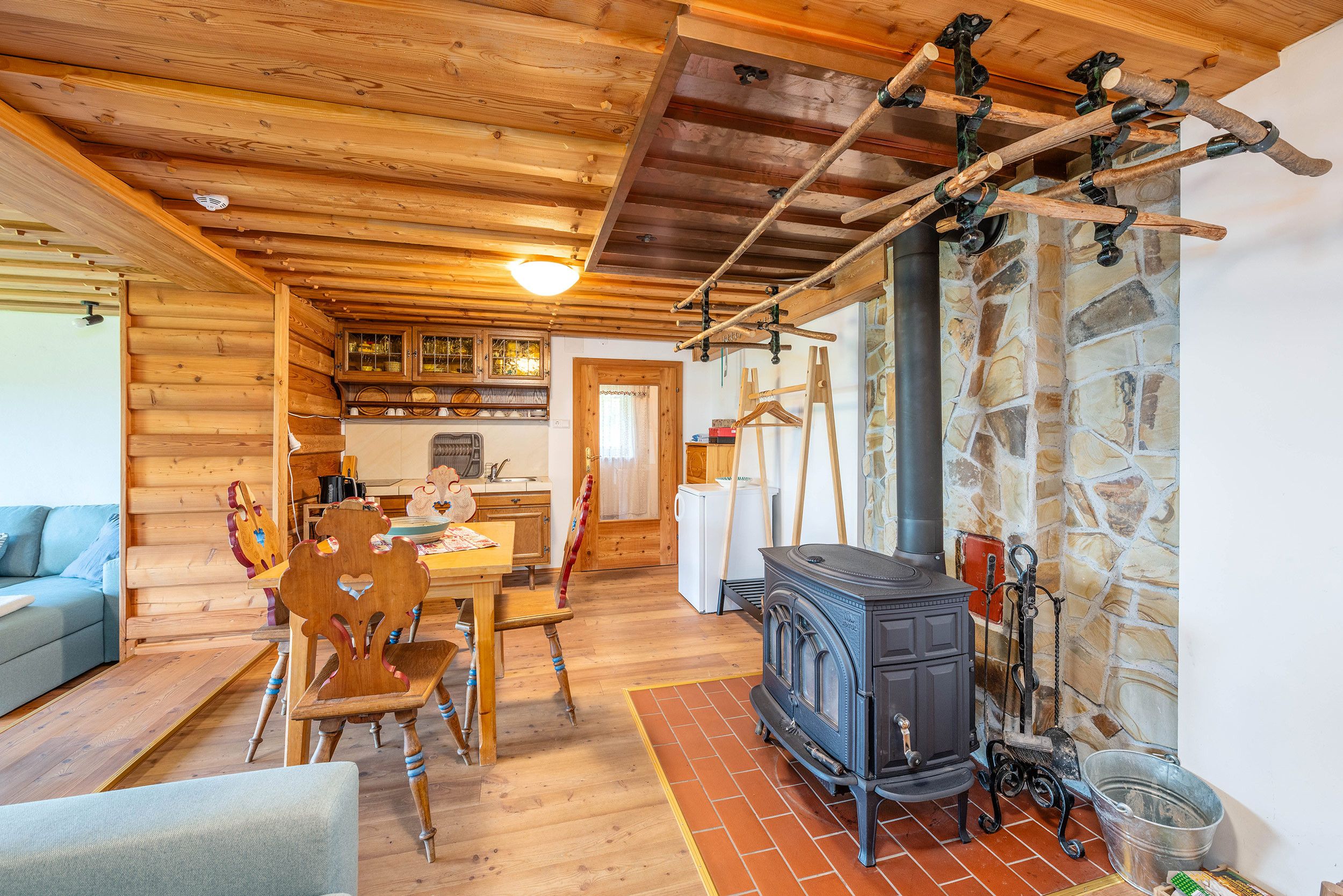 A rustic wooden interior with a dining area, kitchen, and a stone wall.