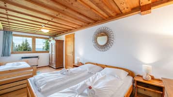 Ein Zimmer mit zwei Holzbetten, einem Spiegel und einem Fenster mit Blick auf Bäume.