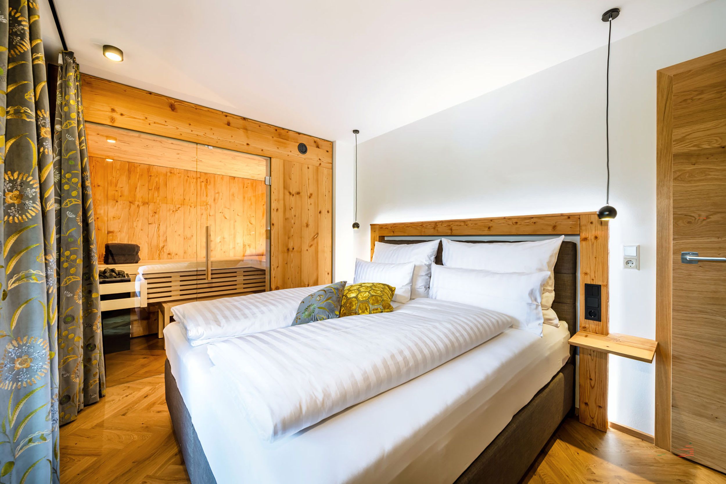 Un dormitorio con cabecera de madera, cama con ropa de cama blanca, mesita de noche y armario de madera.