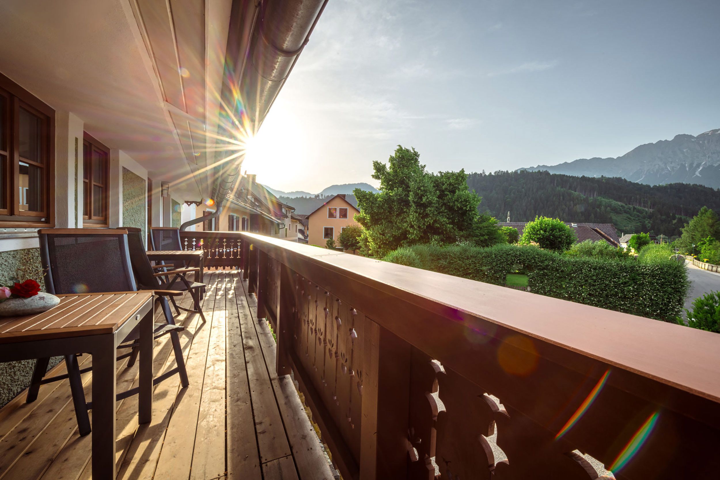 Un terrazzo in legno con vista sulle montagne e un cielo sereno.