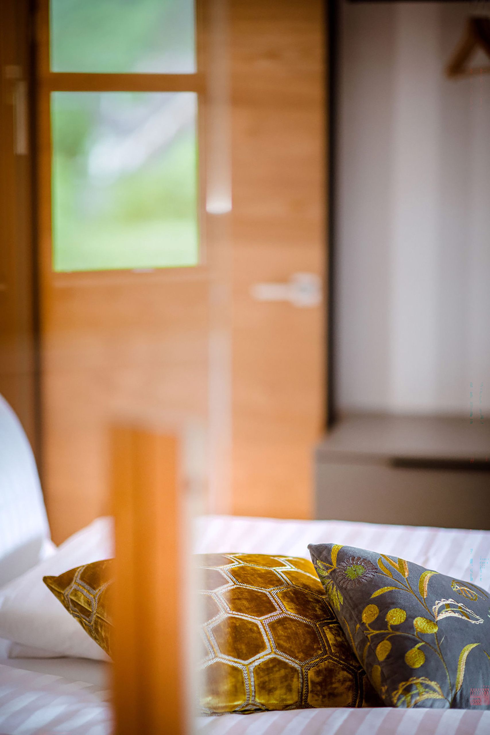 Un letto con cuscini fantasia e una testiera in legno.