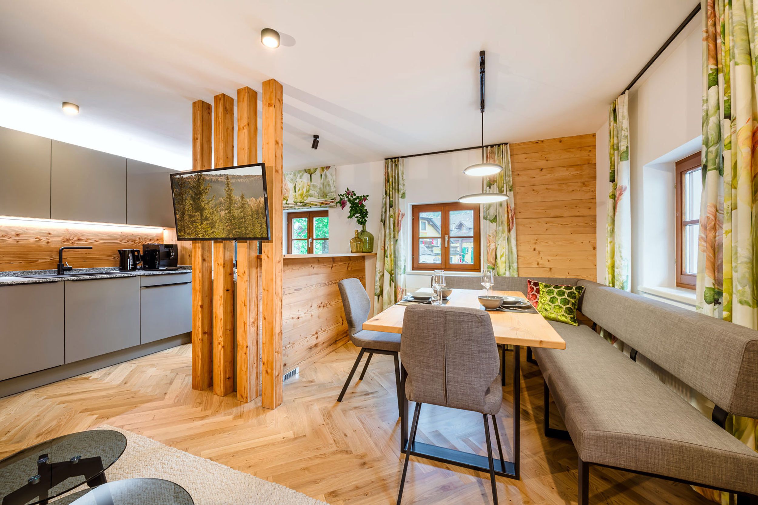 Una cocina moderna con detalles de madera, un comedor con mesa y sillas, y un sofá.