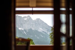 Vista sulle montagne attraverso una finestra con una prospettiva su una catena montuosa.